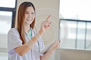 Happy smiling young beautiful female doctor showing blank area f