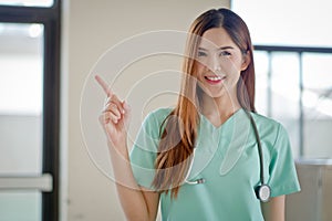 Happy smiling young beautiful female doctor showing blank area f