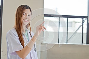 Happy smiling young beautiful female doctor showing blank area f