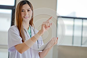 Happy smiling young beautiful female doctor showing blank area f