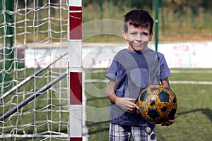 Happy smiling young boy with football ball