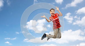 Happy smiling young boy jumping in air over sky
