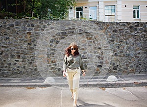 happy smiling young brunette woman in sunglasses walking along the city street