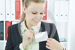 Happy smiling young business woman wearing blank badge.