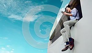 Happy Smiling Young Businessman in Casual wear Using Mobile Phone at the high rooftop Urban City Sky