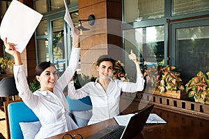 Happy smiling young businesswomen working on laptop in street cafe outdoor