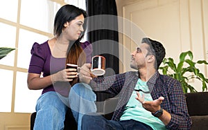 Happy smiling young couple having tea or coffee while talking each other at home - concept of family time, couple