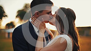 Happy smiling young couple in love outdoors. Kissing. Colorful sunset. Wedding day.