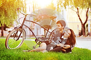 Happy smiling young couple lying in a park near a vintage bike
