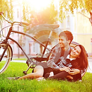 Happy smiling young couple lying in a park near a vintage bike