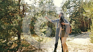 Happy, smiling young couple, man and woman in casual clothes walking in forest on warm day, enjoying nature, talking