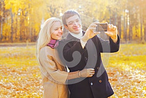 Happy smiling young couple together taking picture self portrait on smarphone in sunny autumn photo