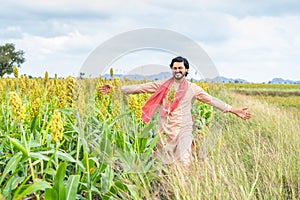 Happy smiling young farmer walking at corn field by feeling nature at framland - concept of happiness, freedom and