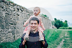 Happy smiling young father with a little cute daughter in pink dress