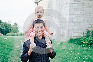 Happy smiling young father with a little cute daughter in pink dress