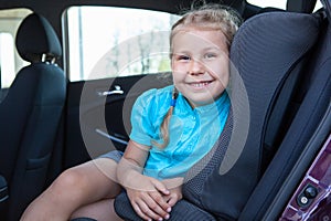 Happy smiling young girl sitting in infant restraint seat