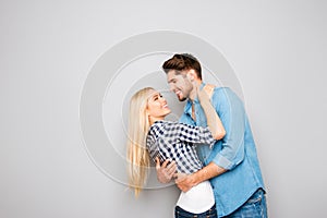 Happy smiling young lovers huging on gray background