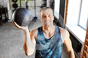 Happy smiling young man with medicine ball in gym