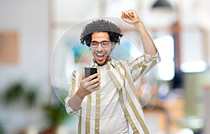 happy smiling young man with smartphone at office