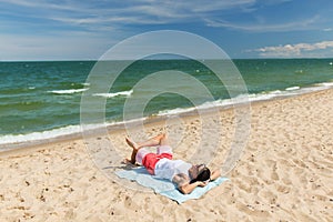 Happy smiling young man sunbathing on beach towel