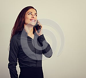 Happy smiling young positive woman with long curly hairstyle in business office clothing talking on mobile phone and looking up.