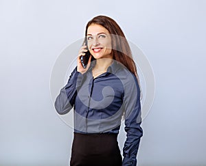 Happy smiling young positive woman with long curly hairstyle in business office clothing talking on mobile phone and looking up on