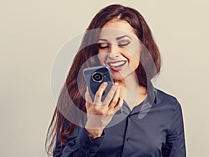 Happy smiling young positive woman with long curly hairstyle in business office clothing talking on mobile phone and looking up on