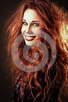 Happy smiling young redhead woman with long curly hair