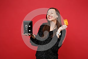Happy smiling young woman in black fur sweater keeping eyes closed, hold metal bank safe for money accumulation, credit