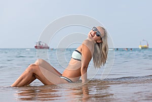 Happy smiling young woman in black sunglasses in the sea in the day time. Positive human emotions, feelings, joy. Spring and summe