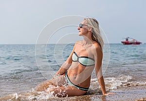 Happy smiling young woman in black sunglasses in the sea in the day time. Positive human emotions, feelings, joy. Spring and summe