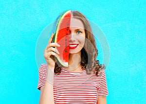 Happy smiling young woman is closing half face with slice of watermelon