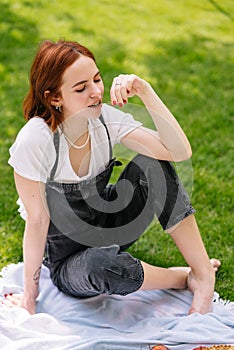 Happy smiling young woman eating cherry of the park lawn