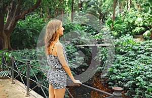 Happy smiling young woman enjoying nature in forest on tropical tree background