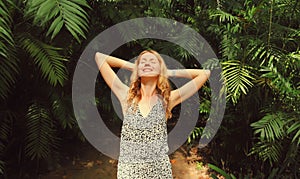 Happy smiling young woman enjoying nature in forest on tropical tree background