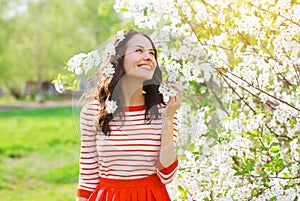 Happy smiling young woman in flowering spring garden