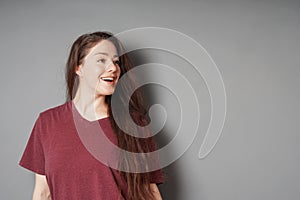 Happy smiling young woman in her 20s with natural make-up and brunette long hair looking to side