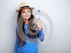 Happy smiling young woman holding bottle of pure water on blue b