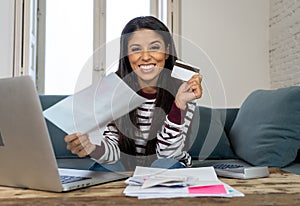 Happy smiling young woman making online payments bills using laptop and credit card