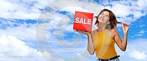 Happy smiling young woman posing with sale sign