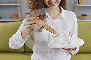 Happy, smiling young woman putting an orthotic insole inside her orthopedic shoes