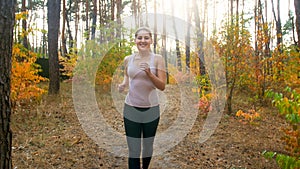 Happy smiling young woman running and doing fitness at autumn forest.