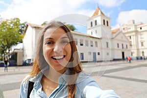 Happy smiling young woman in Sao Paulo city center take self portrait with Patio do Colegio landmark on the background, Sao Paulo photo