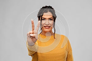 Happy smiling young woman showing peace sign