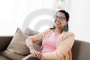 Happy smiling young woman sitting on sofa at home