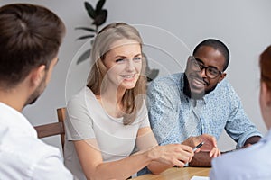 Happy smiling young woman talking with coworkers at work