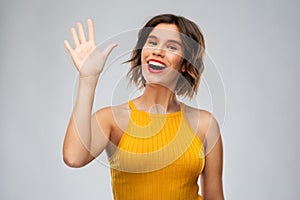 Happy smiling young woman waving hand