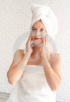 Happy smiling young woman in white bath towels doing spa procedures