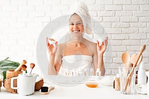 Happy smiling young woman in white bath towels smelling the cream doing spa procedures