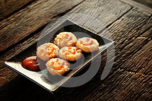 Happy snack with Chicken nugget with smile tomato sauce in black plate on rough wooden